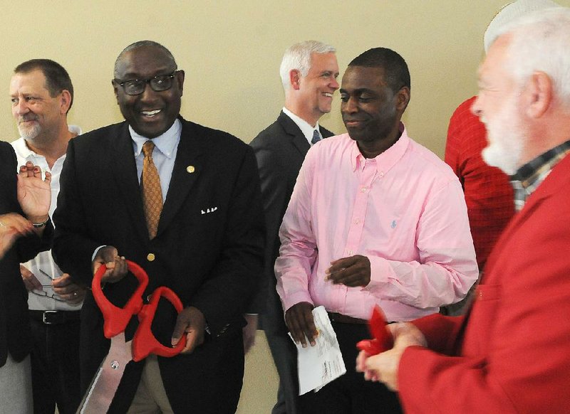 Sherman Tate, chairman of the Urban League of Arkansas (with scissors), and D’Andre Jones, a board member, attend a ribbon-cutting ceremony Friday for the Springdale office of the Urban League.