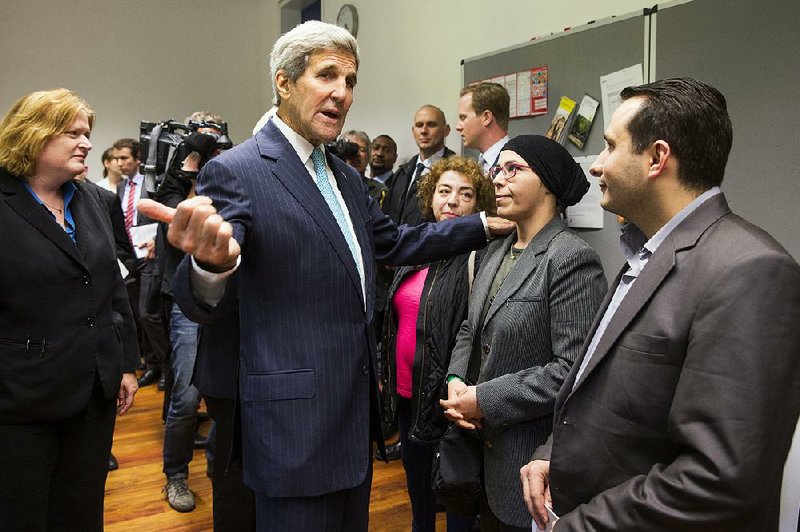 U.S. Secretary of State John Kerry meets with people fl eeing Syria at Villa Borsig in Berlin on Sunday. 

