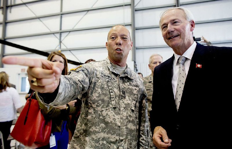 Capt. Steven Thompson shows Gov. Asa Hutchinson how to read various ranks on uniforms Monday after a news conference at Camp Robinson in North Little Rock.