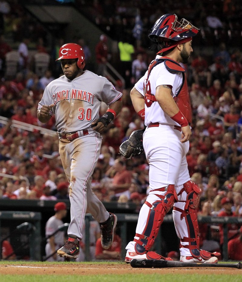 Cincinnati Reds' Jason Bourgeois, left, scores past St. Louis Cardinals catcher Tony Cruz, right, on a single by Brandon Phillips during the first inning of a baseball game against the St. Louis Cardinals on Monday, Sept. 21, 2015, in St. Louis.