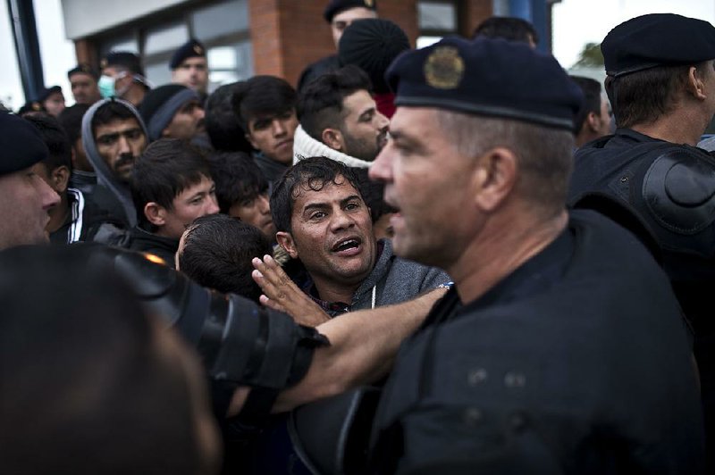 A policeman pushes back a migrant Tuesday at a registration center for asylum seekers in Opatovac, Croatia. 