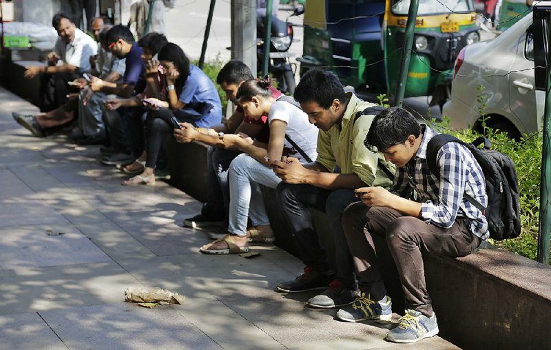 Indians check their mobile phones in New Delhi on Tuesday. India’s prime minister plans to visit Silicon Valley next week to talk to leaders at Facebook, Google, Apple and Tesla Motors. 