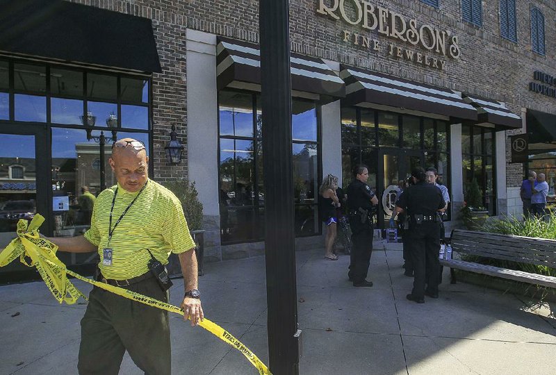 Little Rock police detective J.C. White removes crime scene tape after investigating an armed robbery at Roberson’s Fine Jewelry in the Pleasant Ridge Town Center on Tuesday afternoon. 