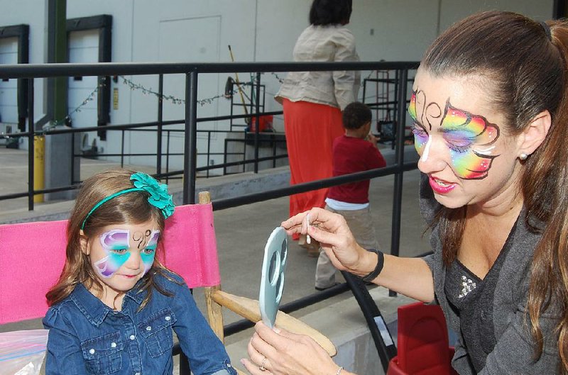 Gabriella Taylor (left) admires the work of face painter Shawna McGill at last year’s Drive Away Hunger event at the Arkansas Foodbank. The Saturday fundraiser includes activities for all ages. 