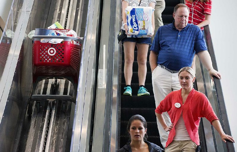 Shoppers ride an escalator at the CityTarget store in Boston in August. The economy grew at a faster clip than estimated in the second quarter, but consumers were less optimistic this month about the economy, according to reports released Friday.