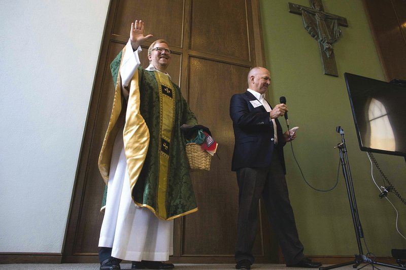 The Rev. Paul McLain waves to parishioners at Trinity Episcopal Cathedral in Little Rock after being presented with gifts from the congregation by Jack Harvey during a farewell gathering on Aug. 30. 