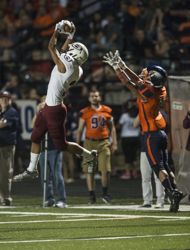 Kyler Williams of Springdale catches a pass in front of Rogers Heritage’s David Zamora during Friday’s game in Gates Stadium in Rogers.