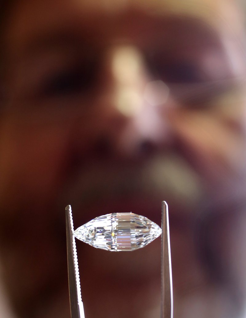 Arkansas Democrat-Gazette/JOHN SYKES JR. The finished Esperanza, a diamond, found by Brooke Oskarson (not pictured) in June at the Crater of Diamonds State Park, is held up by Mike Botha. Botha cut the diamond into its final shape.