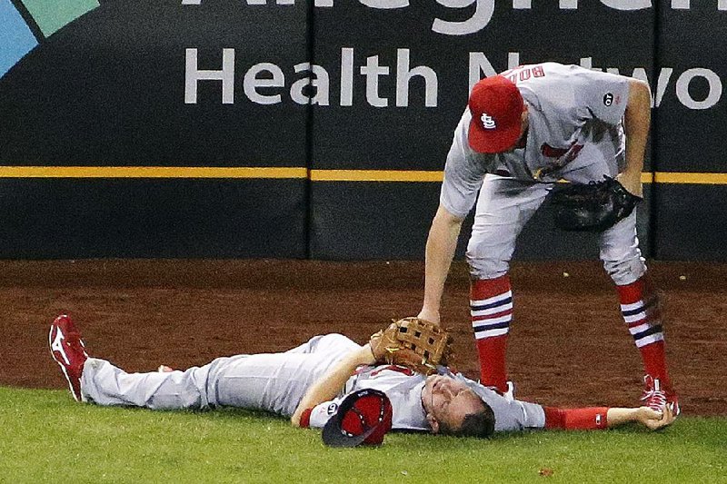 St. Louis center fielder Peter Bourjos (right) checks on teammate Stephen Piscotty after the two collided while trying to catch a fly ball during the ninth inning of Monday’s game against Pittsburgh. The Cardinals managed to hold on for a 3-0 victory.
