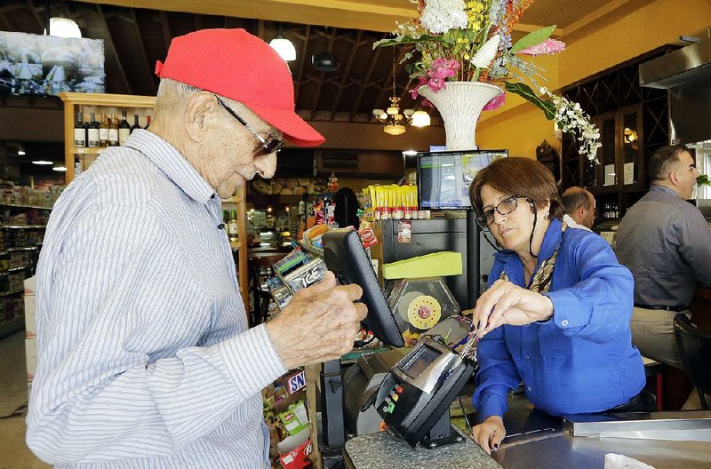 A cashier helps a shopper swipe a credit card at a grocery store in Miami’s Little Havana neighborhood in June. A business research group said Tuesday that its consumer confidence index rose in September after surging in August. 