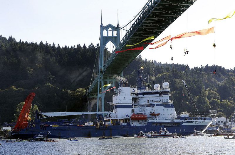 The Royal Dutch Shell PLC icebreaker Fennica, bound for Alaska, heads up the Willamette River in Portland, Ore., on July 30 under protesters hanging from the St. Johns Bridge. Royal Dutch Shell said Monday it has ceased exploration in Arctic waters off Alaska’s coast. 