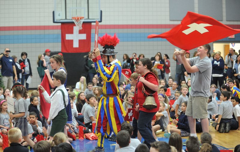 St. Vincent de Paul Catholic School students dressed in Swiss attire and carrying Swiss flags march into the gym Friday morning in the processional of countries during the schools 13th annual World Experience Day in Rogers.  This year students explored the sights, tastes and history of Switzerland. 