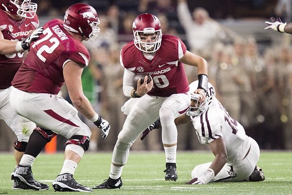 Arkansas senior quarterback Brandon Allen slips out of a sack attempt by Texas A&M junior defensive end Daeshon Hall on Saturday, Sept. 26, 2015, at AT&T Stadium in Arlington, Texas.