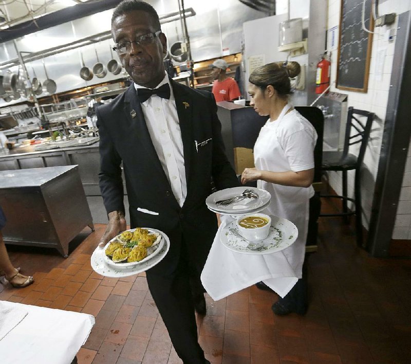 Waiter Austin Murray brings plated dishes to the dining room at Antoine’s Restaurant in New Orleans, celebrating its 175th birthday. 