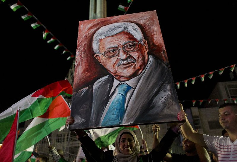 A woman waves a portrait of Palestinian President Mahmoud Abbas on Wednesday in the West Bank city of Ramallah after Abbas’ speech to the U.N. General Assembly. 