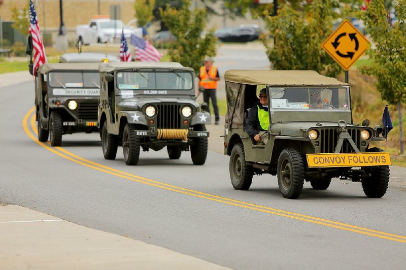 A row of retired Army jeeps rolls into MacArthur Park in Little Rock on Wednesday as part of a convoy of vintage military vehicles that is retracing the route of a 1920 U.S. Army convoy.