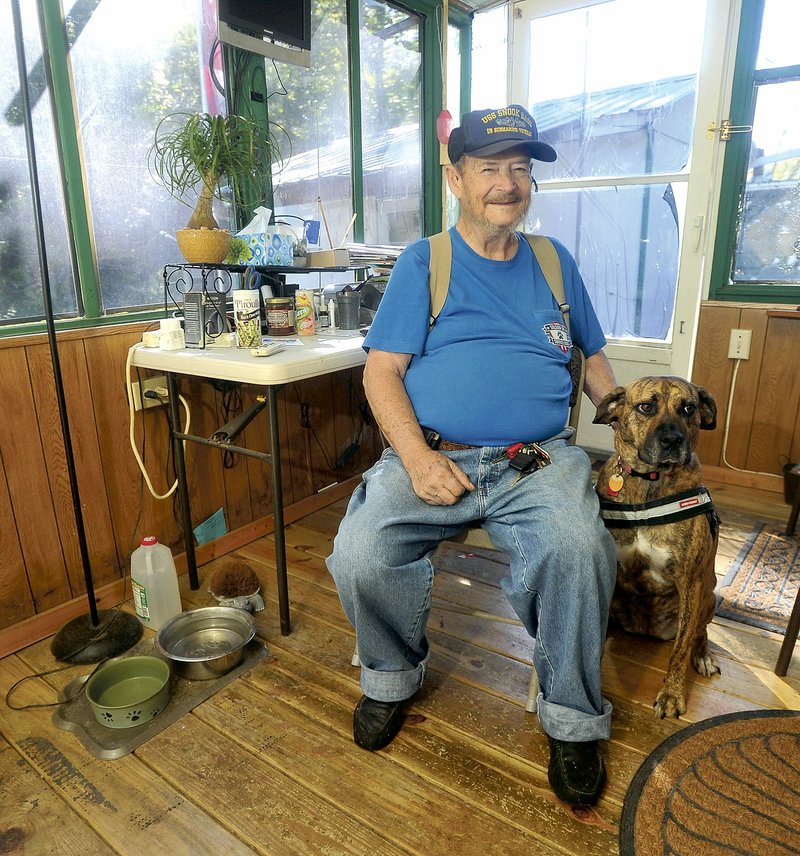 Richard Ellett, a veteran with PTSD, sits in his front room with Tiger, the service dog he received in November. The service dog was given to Ellett by Soldier ON. The new nonprofit organization places puppies with puppy-raisers for one year to be trained as service dogs, then gives the dogs to veterans with PTSD.