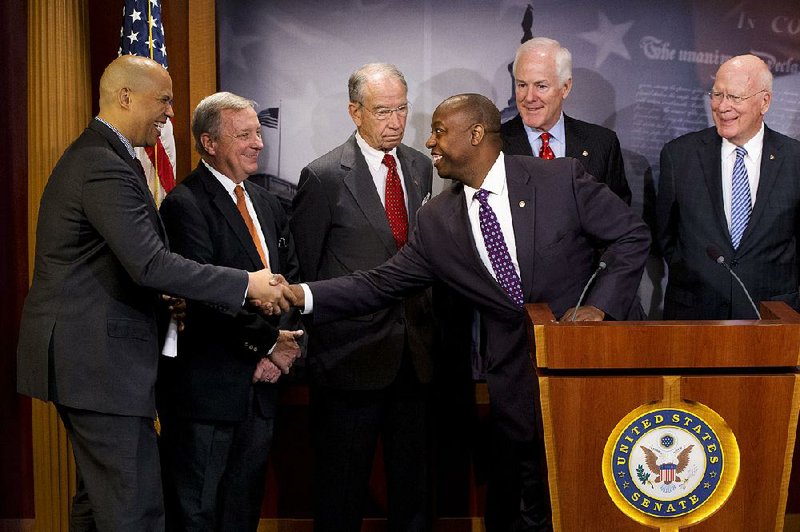 Sen. Tim Scott, R-S.C., greets Sen. Cory Booker, D-N.J., while speaking about a criminal-justice overhaul at a news conference with a bipartisan group of senators Thursday in Washington. 