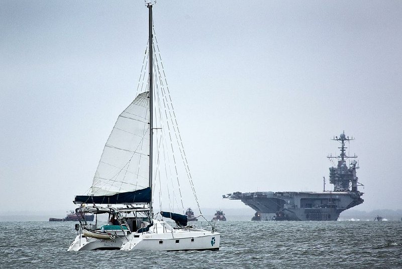 The USS Harry S. Truman returns to Norfolk ahead of Hurricane Joaquin as a catamaran sails by Thursday in Hampton, Va. 