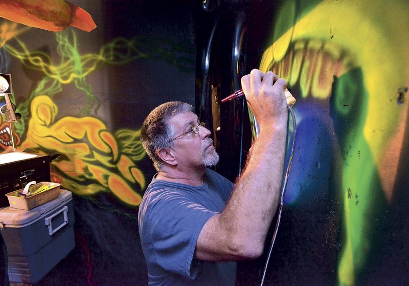 Danny Smith works on a 3-D blacklight mural inside Nightmares Haunted House in Bentonville last year. Regional Halloween attractions begin opening this weekend.