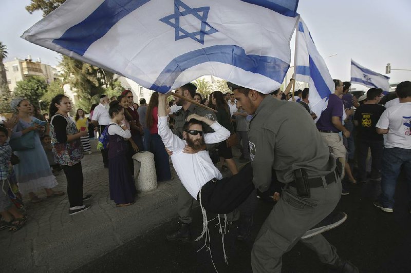 A man tussles with police Friday in Jerusalem as a crowd protests over the slayings Thursday of a Jewish settler couple in the West Bank.