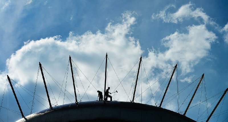 Painters work on a water tank last month in Delano Park in Decatur, Ala. Cuts in manufacturing and oil-drilling jobs dragged down hiring fi gures for September.
