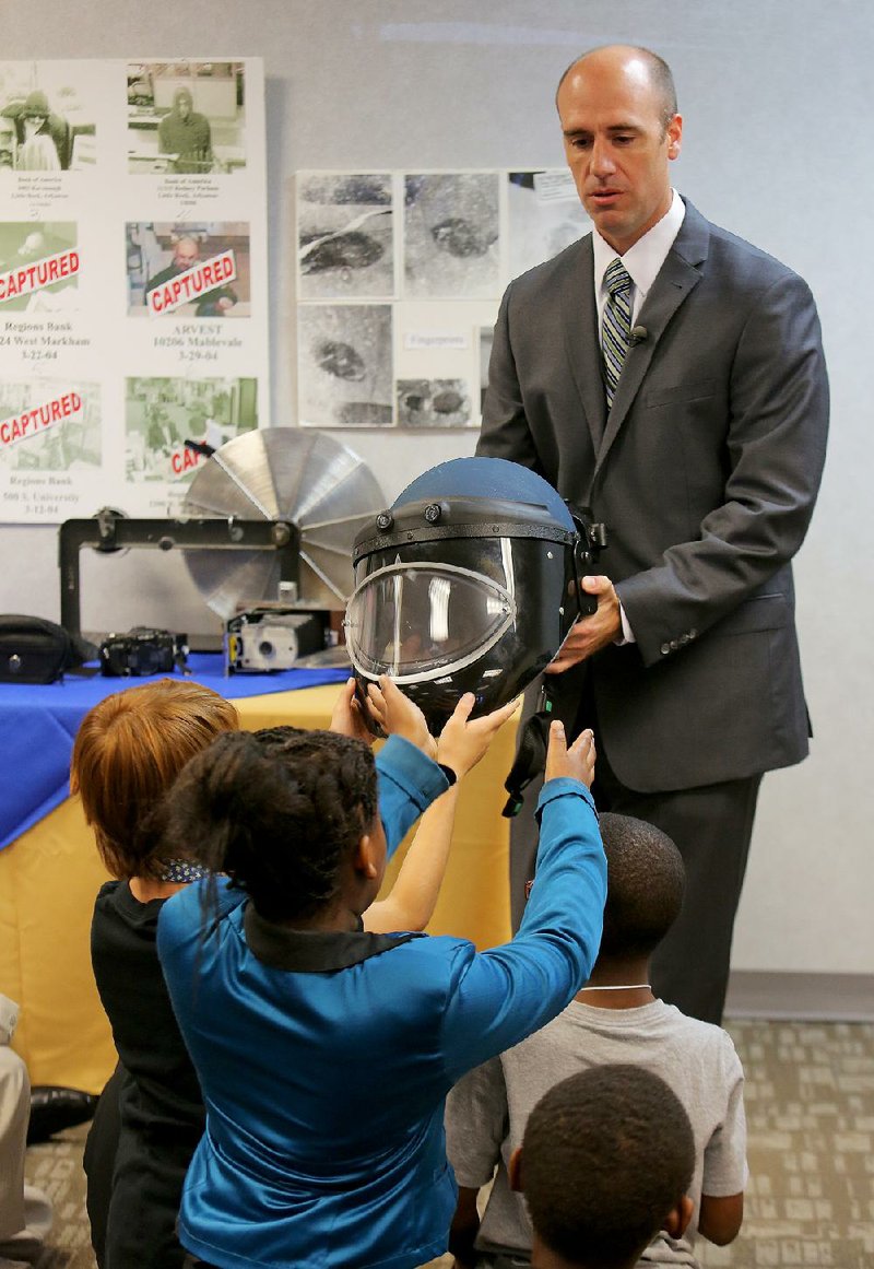 Special Agent Ryan Kennedy shows a bomb-blast helmet to fifth-graders from Gibbs Elementary School during the students’ field trip to the FBI’s Little Rock office. 