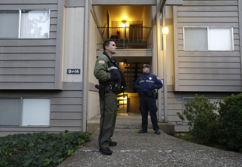 Douglas County Deputy Greg Kennerly (left) and Oregon State Trooper Tom Willis stand guard Friday outside the apartment building in Roseburg, Ore., where gunman Chris Harper-Mercer lived.

