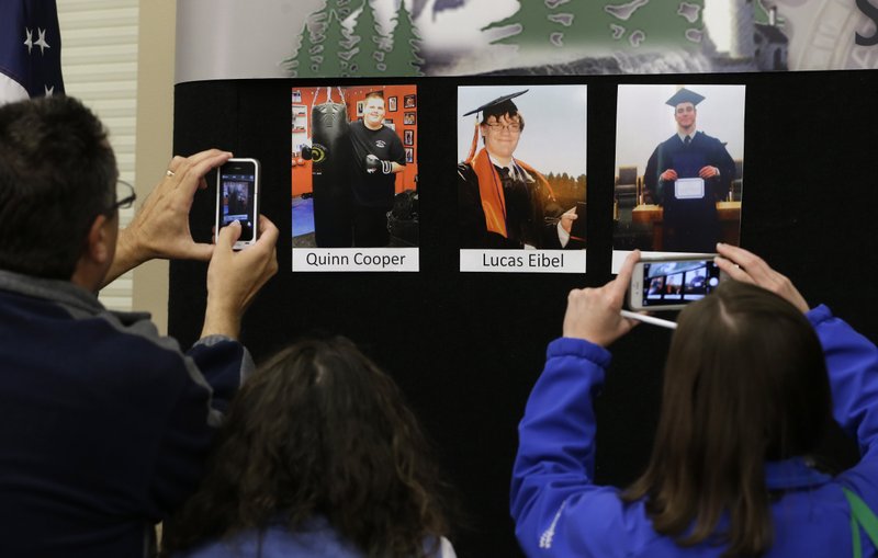 Reporters copy photographs of three of the victims of the mass shooting at Umpqua Community College that were displayed at a news conference, Friday, Oct. 2, 2015, in Roseburg, Ore. In the photos, from left, are Quinn Cooper, 18, Lucas Eibel,18, center, and Jason Johnson, 33. They were among those killed when Chris Harper Mercer walked into a class at the community college the day before and opened fire. 