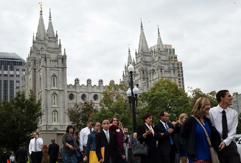 People walk in Temple Square after arriving Saturday for the opening session of the two-day Mormon church conference in Salt Lake City. 