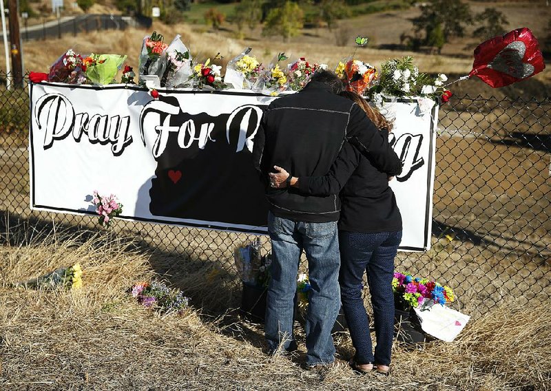 Charley Thompson and his wife, Rachel, place flowers at a memorial Saturday near the road leading to Umpqua Community College in Roseburg, Ore. 