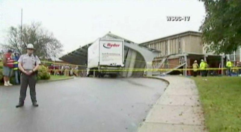 In this frame from video provided by WSOC, officials stand near a concrete canopy that collapsed Saturday, Oct. 3, 2015, in Olin, N.C. A box truck hit one of the canopy supports and the awning then fell on a group of band students.