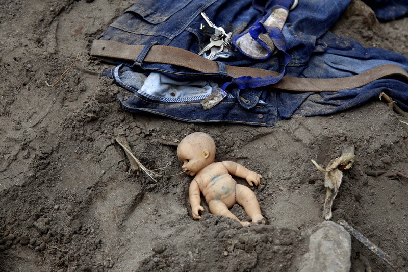 A doll and clothing lay in the mud as rescue workers continue to search the site of a mudslide in Cambray, a neighborhood in the suburb of Santa Catarina Pinula, on the outskirts of Guatemala City, Saturday, Oct. 3, 2015. Rescue workers recovered more bodies Saturday after a hillside collapsed on homes late Thursday, while more are feared still buried in the rubble. 