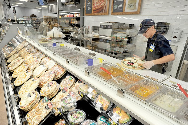 Wal-Mart employee David Weyer makes a pizza Wednesday in the newly remodeled deli area at the Pleasant Grove Wal-Mart location in Rogers.
