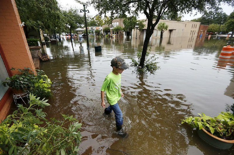 Tripp Adams, 8, walks through floodwaters near high tide Sunday in the historic downtown of Georgetown, S.C. Much of South Carolina experienced fl ooding when record rainfall combined with an unusually high lunar tide.