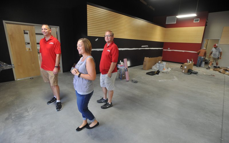 Tony Baker (from left) Christina Baker and Gregg Price, Arkansas Music Works owners, walk through the main room of their new store Sept. 23 as workers prepare it for the grand opening in early October. The new location will include more warehouse space for their online sales services as well more classroom space for music lessons. For more photos, go to www.nwadg.com/photos.