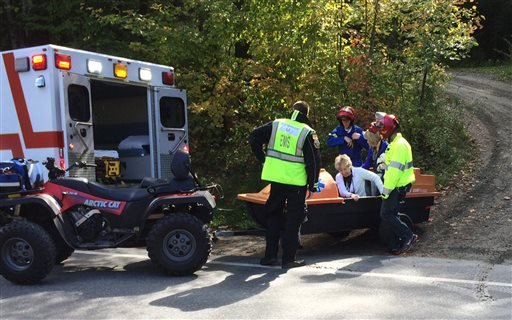 Emergency first responders assist a woman, center, as she is transferred to an ambulance from a trailer attached to an all-terrain vehicle near the site of an Amtrak train derailment Monday, Oct. 5, 2015, in Roxbury, Vt.