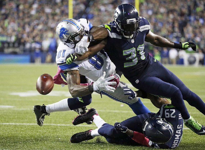 Seattle safety Kam Chancellor (right) knocks the ball loose from Detroit wide receiver Calvin Johnson just before Johnson crosses the goal line late in the fourth quarter of Monday night’s game in Seattle. The touchback, allowed to stand when an apparent infraction by the Seahawks wasn’t flagged, gave Seattle the ball at its 20 and allowed it to run out the clock on a 13-10 victory. 