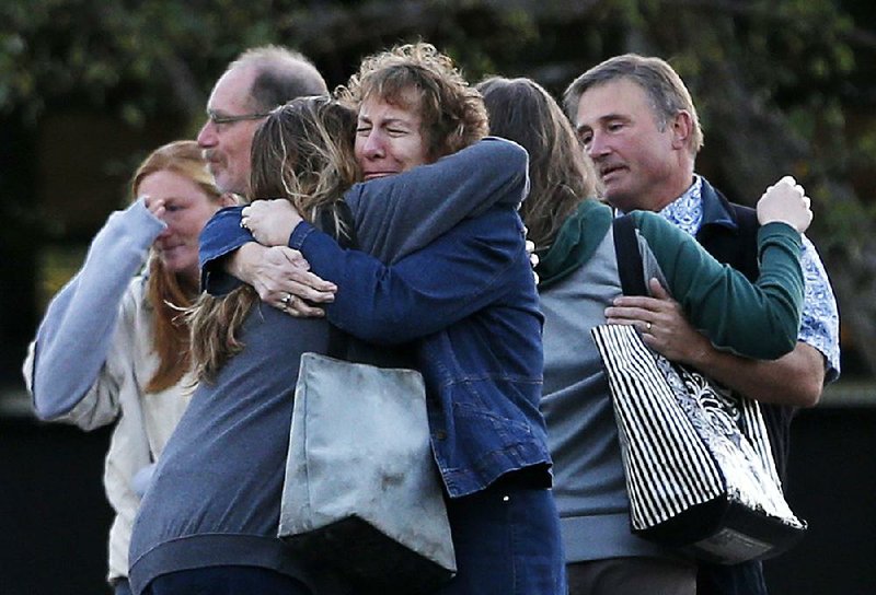 Faculty members embrace Monday as they are allowed to return to Umpqua Community College in Roseburg, Ore. The campus reopened to faculty for the fi rst time since Thursday, when armed suspect Chris Harper-Mercer killed multiple people and wounded several others before taking his own life at Snyder Hall.