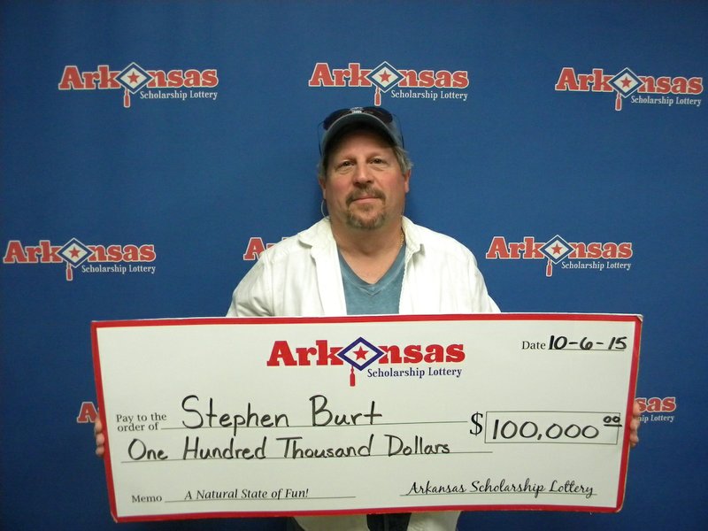 Van Buren resident Stephen Burt stands with his $100,000 check from the Arkansas Scholarship Lottery on Tuesday, Oct. 6, 2015.