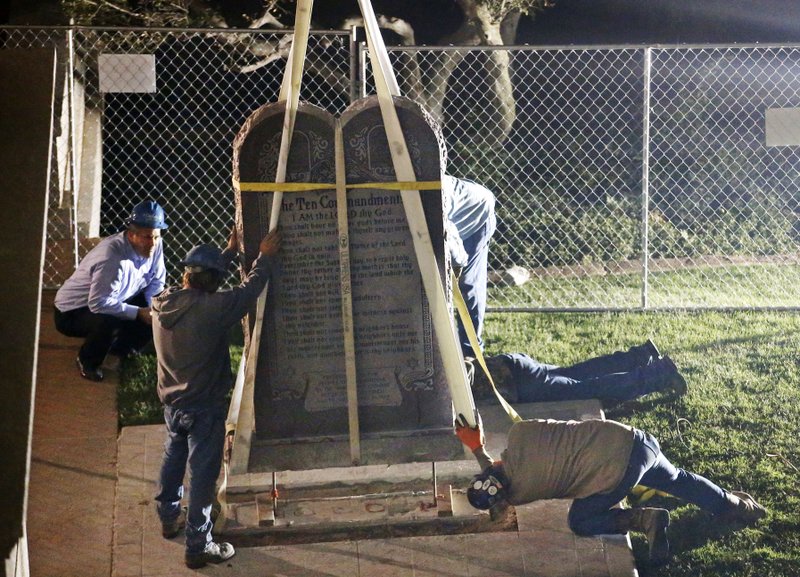 Workers remove the Ten Commandments monument from its base on the grounds of the state Capitol in Oklahoma City, Monday, Oct. 5, 2015. The removal comes after the Oklahoma Supreme Court's decision in June that the display violates a state constitutional prohibition on the use of public property. (AP Photo/Sue Ogrocki)
