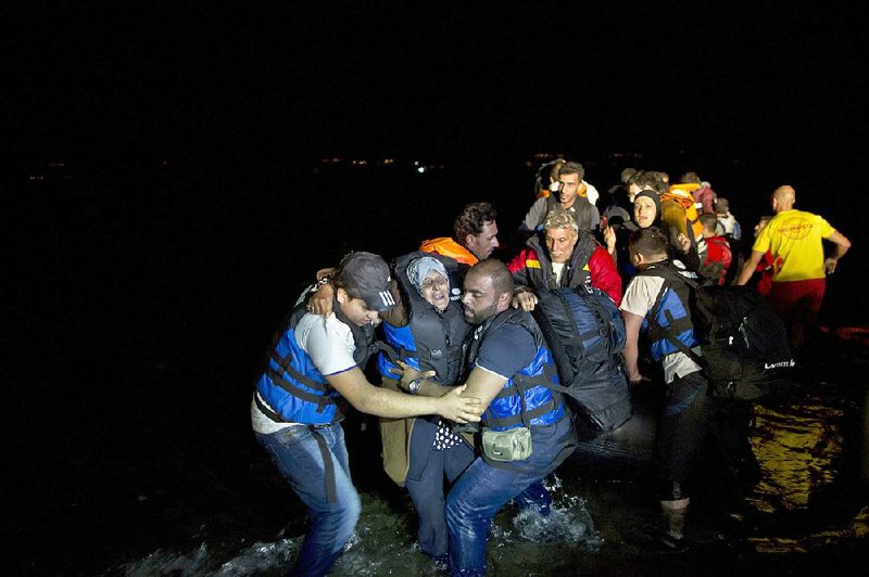 Syrian refugees try to carry an elderly woman off a dinghy as it arrives Tuesday from the Turkish coast to the northeastern Greek island of Lesbos. 