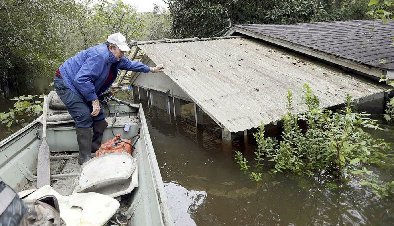 Jackie Lee looks at the flooding Tuesday at property he owns along the Lynches River in Effingham, S.C., as the sun finally came out after days of rain. Homeowners began prying open swollen doors and tearing out ruined carpets, but state officials warned that more flooding was possible, with several rivers yet to crest. 
