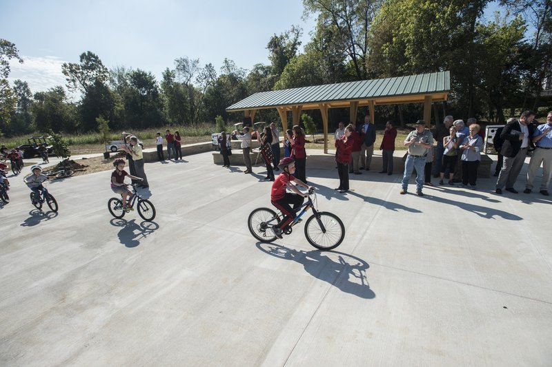 Students from J.B. Hunt Elementary School ride through for a ceremonial opening Tuesday for the trailhead at Silent Grove Road and Pump Station Road in Springdale. The trailhead leads to the Razorback Greenway, J.B. Hunt Park and a new mountain bike skills course and trail. The students are part of the school’s bicycle education program where they learn how to ride, bike safety and maintenance.