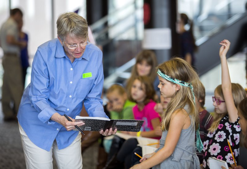 Lois Lowry, two-time Newbery Award winner and author of The Giver and Night of a Thousand Stars, looks over story ideas from Washington Elementary second-grader Sydney Coleman on Wednesday at the Fayetteville High School library.