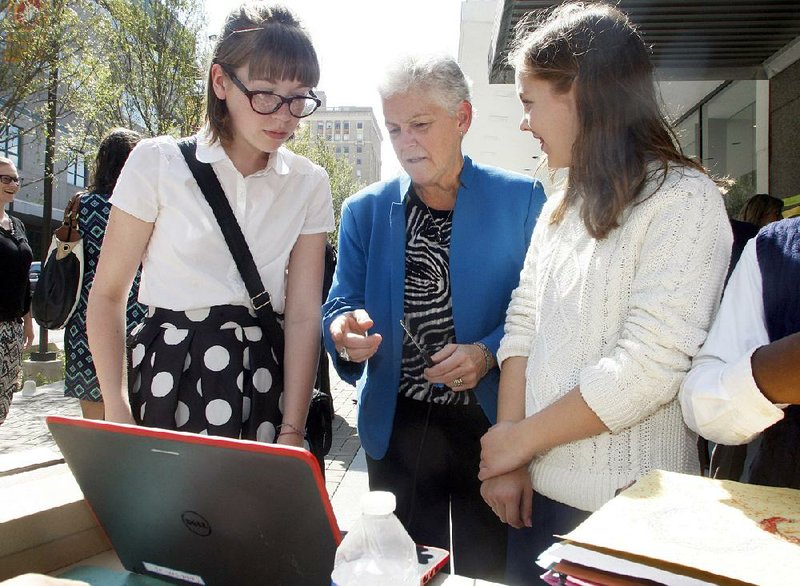 EPA Administrator Gina McCarthy (center) talks Wednesday with eStem students Catherine Roxburgh (left) and Cecelia Rech about an environmental science experiment they’ve been conducting in the Creative Corridor along Main Street in downtown Little Rock. 