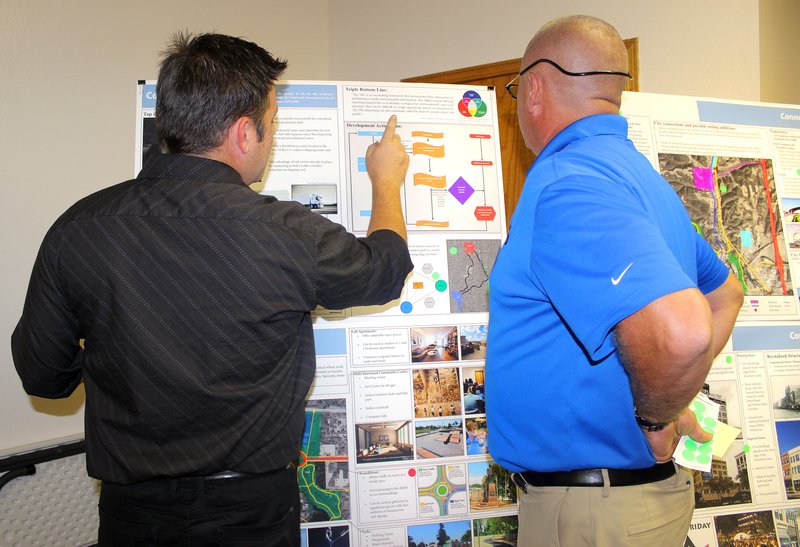 MEGAN DAVIS MCDONALD COUNTY PRESS Architectural student Brad Davenport explains to resident Eric Cochran how using the Triple Bottom Line formula, an accounting framework, could benefit Anderson.