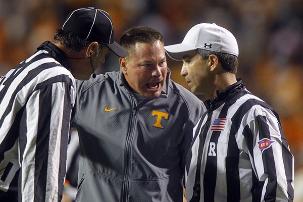 Tennessee head coach Butch Jones argues with referee Marc Curles, right, as head linesman John Langlois listens during the second half of an NCAA college football game against Arkansas Saturday, Oct. 3, 2015 in Knoxville, Tenn. Arkansas won 24-20. (AP Photo/Wade Payne)
