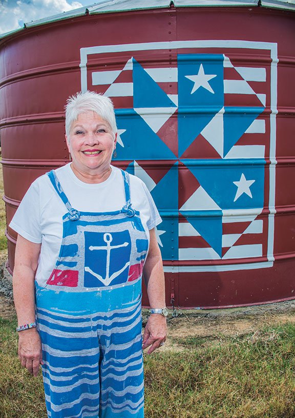 Debbie Park stands next to a barn quilt, a variation of a pinwheel pattern, that she painted on a silo on the Double D Lazy T Ranch in Perryville, where she and her husband, Tommy, live and run a bed-and -breakfast. She saw barn quilts in a magazine and started painting them on pieces of wood to display on her outbuildings. She has completed seven, to date.