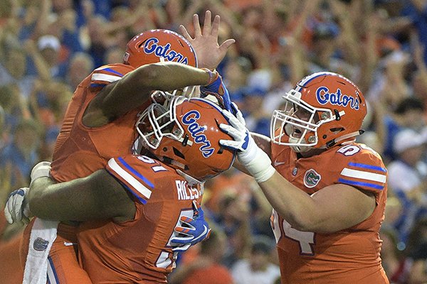 Florida wide receiver Demarcus Robinson, left, is congratulated by offensive lineman Antonio Riles (51) and offensive lineman Cameron Dillard (54) after catching a 36-yard pass in the end zone for a touchdown during the first half of an NCAA college football game against Mississippi Saturday, Oct. 3, 2015, in Gainesville, Fla. (AP Photo/Phelan M. Ebenhack)